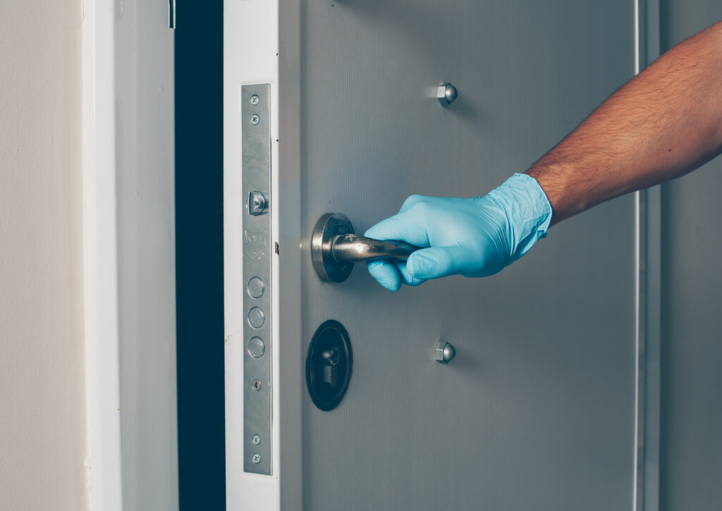 A person opening the door with a gloves on his hands