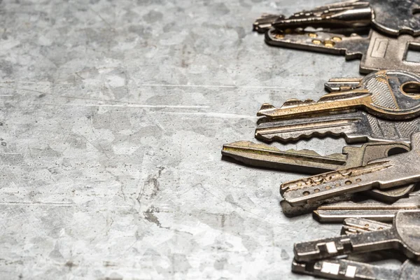 Several old keys on metal surface showing rekey locks or change locks option.