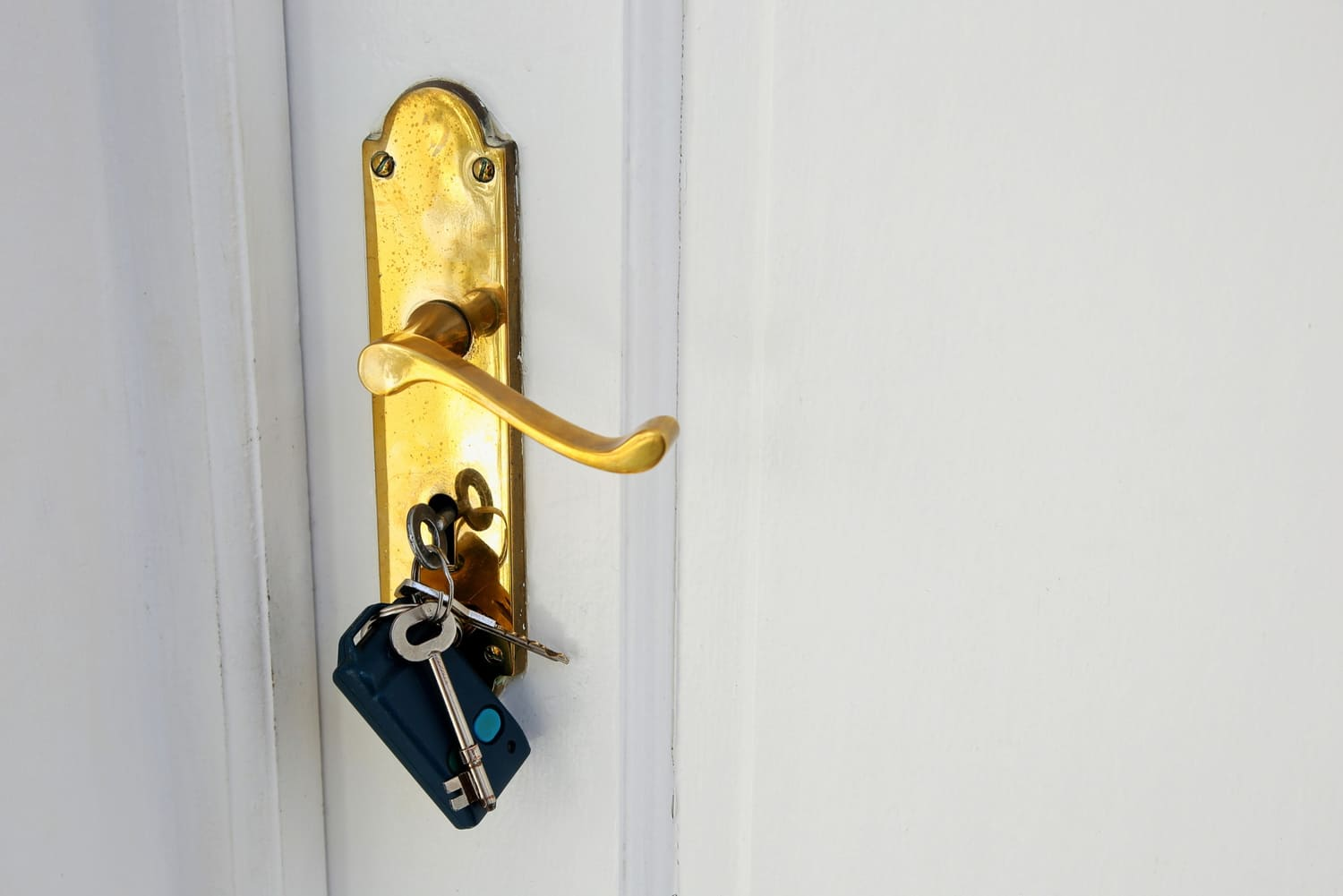 Golden doorknob with lock keys on a white door.